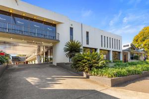 a large white building with plants in front of it at Comfort Inn Grammar View in Toowoomba