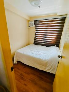 a small bedroom with a white bed with a wooden floor at Seawind in Davao City +6 photos