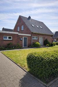 a red brick house with a grass yard at Ferienwohnungen Avenor in Norden