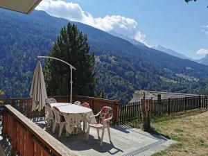 a table and chairs on a balcony with a view of mountains at Le balcon de Mâche in Hérémence