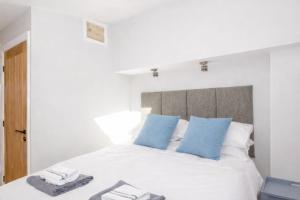 a bedroom with a white bed with blue pillows at The View at 52, Whitby in Whitby