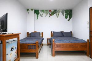 two beds in a room with a tv and a tv at My Friends Hotel in Trang