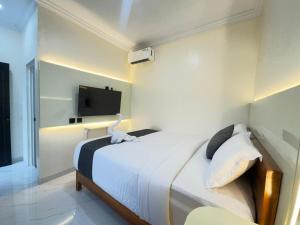 a bedroom with a bed with a tv on the wall at Kalandra Living in Yogyakarta