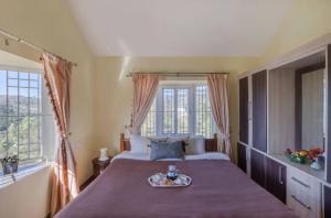 a bedroom with a bed with a tray of food on it at Willostays Cloudhill ooty in Ooty