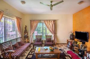 a living room with a couch and chairs and a tv at Willostays Cloudhill ooty in Ooty