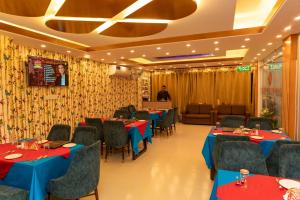 a restaurant with blue tables and chairs and a man standing in the background at Hotel Tawhid in Rangpur