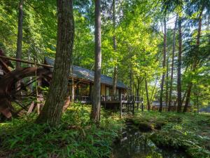 a log cabin in the woods with a tree at Wanosato in Takayama