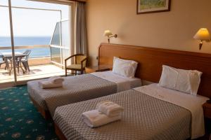 two beds in a hotel room with a view of the ocean at Cavo D' Oro in Piraeus +27 photos