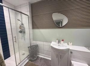 a bathroom with a shower and a sink and a mirror at Spacious 3-Bed Terrace, Great Links in Stowmarket