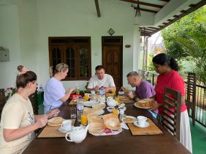 a group of people sitting around a table eating food at White Eagle Hotel in Sigiriya