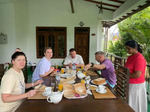 a group of people sitting around a table eating food at White Eagle Hotel in Sigiriya +32 photos