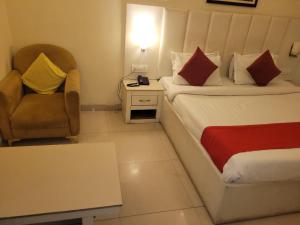 a hotel room with a bed and a chair at Tulip Palms in Jaipur
