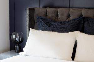 a bed with a black headboard and white pillows at Central Cheltenham Luxury Apartment – Edmonstone House in Cheltenham