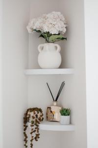 a white shelf with a vase and flowers on it at Central Cheltenham Luxury Apartment – Edmonstone House in Cheltenham