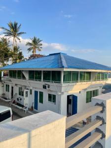 a house with a blue roof with palm trees at HUBIBI Villa Staycation Balayan in Sepaco