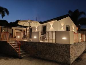 a house with a balcony with an umbrella at Villa Feluchia Tra Il Mare E Il Vulcano in Acireale