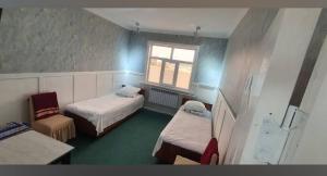 a room with two beds and a window at Umid Hostel in Qŭnghirot