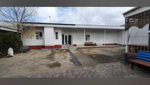 a white building with a bench in front of it at Umid Hostel in Qŭnghirot