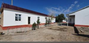 a white building with a fence around it at Umid Hostel in Qŭnghirot