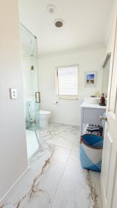 a white bathroom with a sink and a mirror at Beach Apartment in Papamoa +10 photos