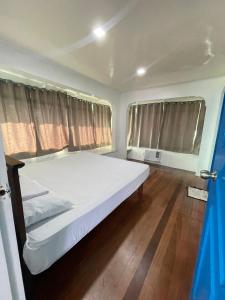 a large white bed in a room with two windows at HUBIBI Villa Staycation Balayan in Sepaco