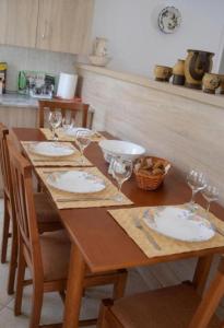 a wooden table with plates and wine glasses on it at Aegina House in Egina +22 photos