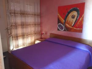a bedroom with a blue bed with a painting on the wall at Augusta Palm Apartment in Bibione