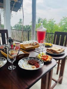 a wooden table with plates of food and a drink at The ransi House in Dickwella +15 photos