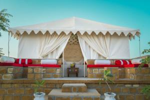 a tent with red and white pillows on a brick wall at Jumeria Grand Luxury Desert Resort & Camp in Jaisalmer