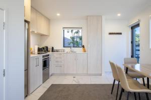a kitchen with white cabinets and a table and chairs at Charming 2-Bedroom Apartment - 2 BR, 1 Bath in Christchurch