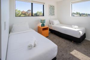 two beds in a room with two windows at Charming 2-Bedroom Apartment - 2 BR, 1 Bath in Christchurch