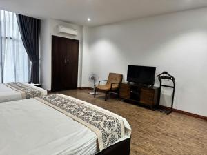 a hotel room with two beds and a flat screen tv at Glory House in An Khê