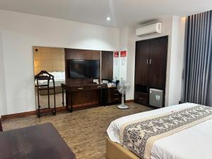 a hotel room with a bed and a flat screen tv at Glory House in An Khê