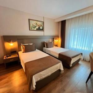 a hotel room with two beds and a window at Adana Time Business Hotel in Adana