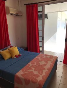a bedroom with a bed with red curtains at Mirimiri guest house in Tahu-Naoe