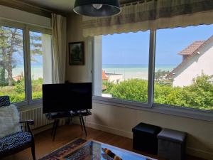 a living room with windows and a flat screen tv at ST MARTIN PLAGE in Saint-Martin-Plage
