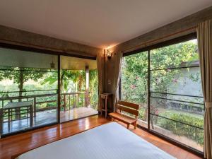 a bedroom with a bed and a balcony with large windows at Lion Cafe Resort in Ban Huai Sieo