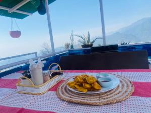 a plate of food on a table with a basket of food at Holistic House in Dharamshala