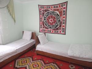two beds in a room with a rug hanging on the wall at Spring Family Guest House in Tersak