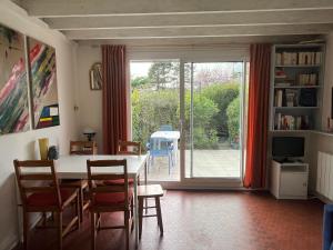 a dining room with a table and chairs and a sliding glass door at Cottage with Garden 5mn Beach in Cabourg
