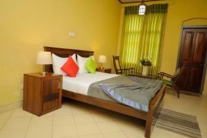 a bedroom with a large bed with colorful pillows at Grosvenor Hotel in Nuwara Eliya +76 photos