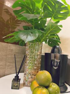 a vase with a plant on a table with lemons at Êm Tiny in Hai Phong