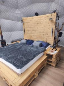 a bedroom with a bed with a wooden headboard at Wild Glamping Liptov in Liptovský Ondrej