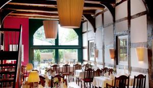 a dining room with tables and chairs and large windows at Schlichte Hof GmbH in Bielefeld