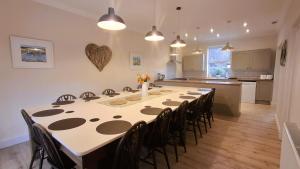 a large kitchen with a long table and chairs at Woodlands in Benllech