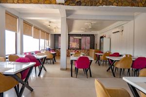 a dining room with tables and pink chairs at Flying Sparrow Riverside Resort in Dhikuli