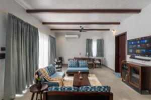 a living room with a couch and a tv at Kaizen Eirene Luxe Villas, Udaipur in Nāi