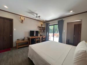 a bedroom with a white bed and a television at Ancarine Beach Resort in Phú Quốc