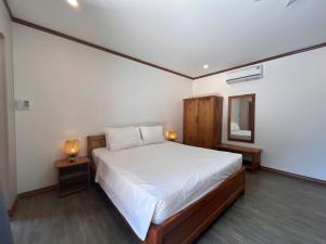 a bedroom with a white bed and a mirror at Ancarine Beach Resort in Phú Quốc