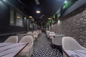 a restaurant with white chairs and a stone wall at Shyanu Lords Eco Inn Airoli-Near Mindspace in Navi Mumbai
